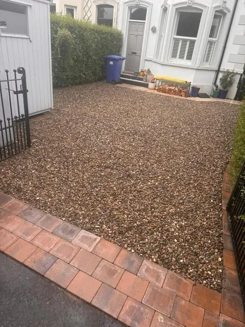 The same front drive after, with fresh gravel and a red block paved edge at the front